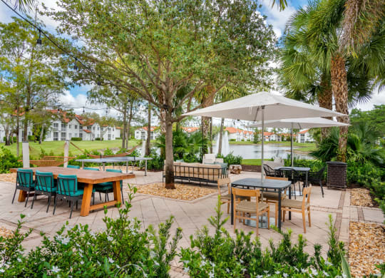 a patio with tables and chairs and trees at The Villas at Ibis Landing, Florida, 33067