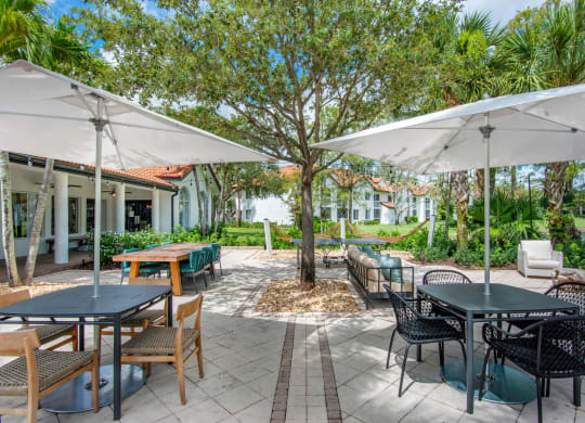 a patio with tables and chairs and umbrellas at The Villas at Ibis Landing, Parkland, 33067