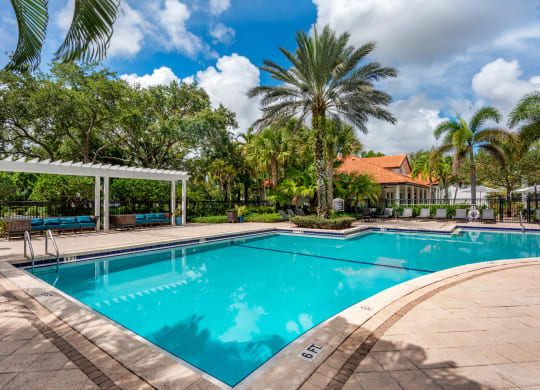 a swimming pool with palm trees and a building in the background at The Villas at Ibis Landing, Parkland, FL