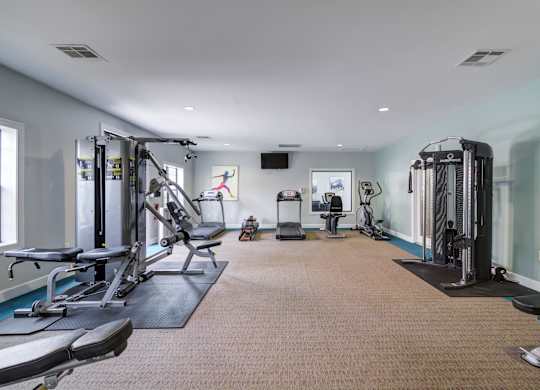 A spacious gym with a variety of equipment including treadmills, weight machines, and benches.