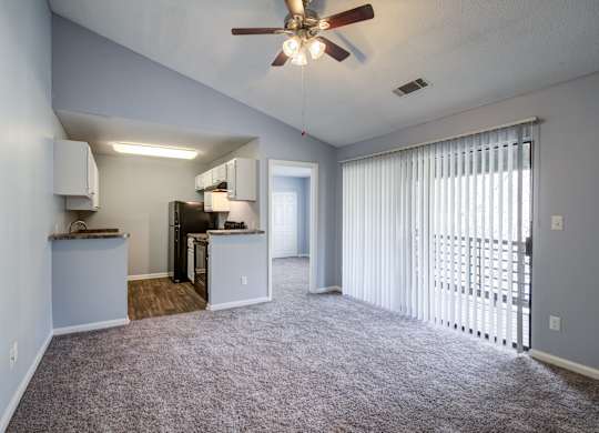 A room with a ceiling fan and carpeted floor.