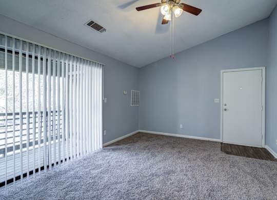A room with a ceiling fan and a window with blinds.