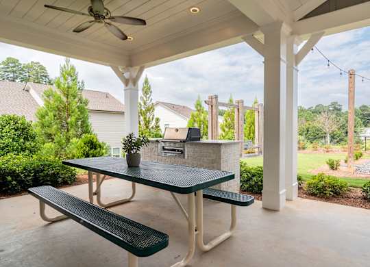 A patio with a table and bench under a roof.