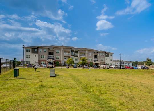 A large grassy field in front of apartment buildings.