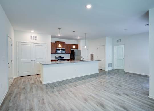 A spacious kitchen with white cabinets and a wooden floor.