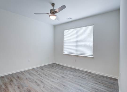 A room with a ceiling fan and a window with blinds.