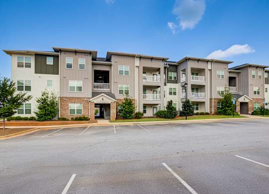 A large apartment complex with a parking lot in front.
