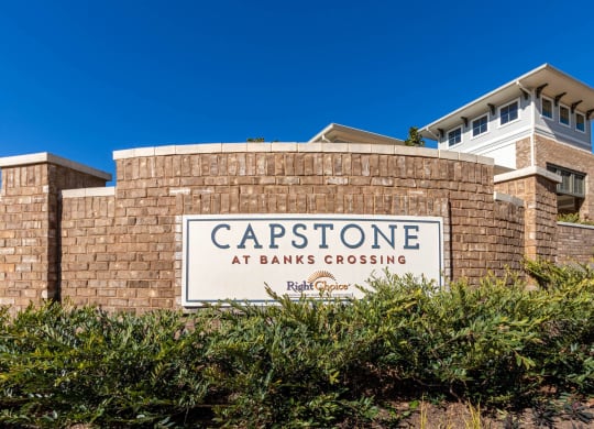 the capstone at banks crossing sign in front of a brick building