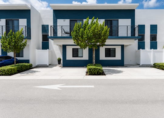 A white and blue building with a tree in front.