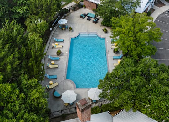 An aerial view of a pool surrounded by trees and chairs.