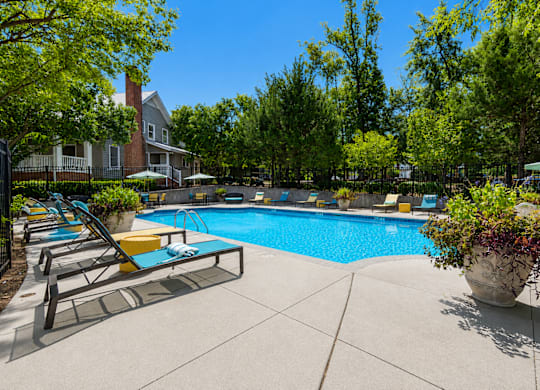 A pool surrounded by trees and a house.