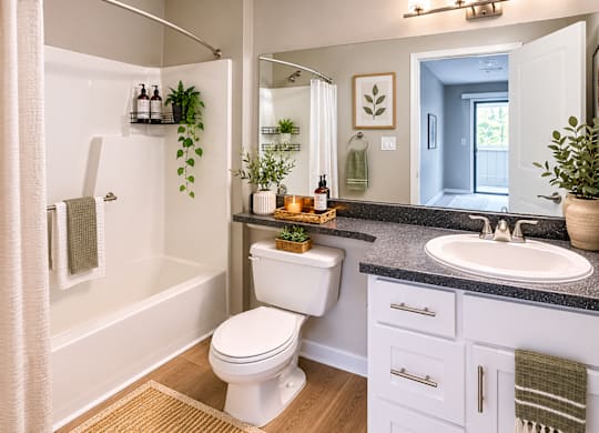 A bathroom with a white toilet, sink, and a shower with a white curtain at Southland Station Apartments in Warner Robins, GA, 31088