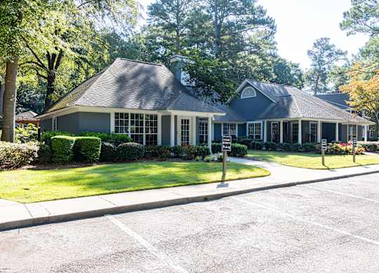 A house with a grey roof and white trim is surrounded by greenery.