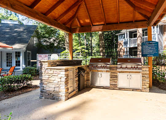 A covered outdoor kitchen area with a grill and sink.