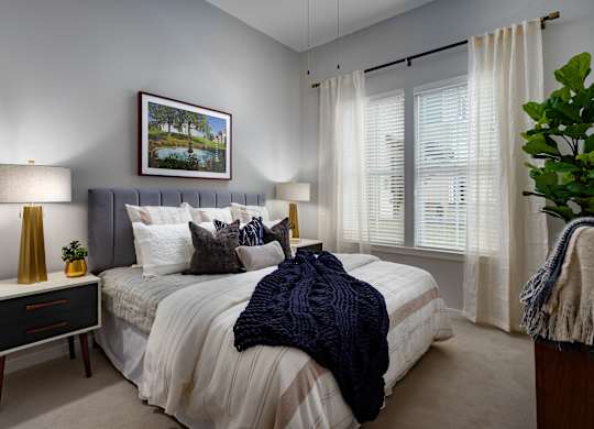 A bedroom with a bed, nightstand, and a painting on the wall.