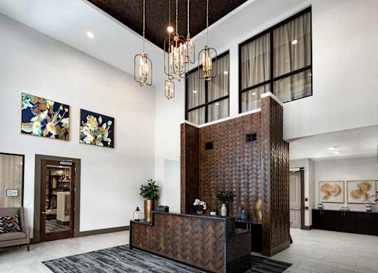 A reception area with a brown wooden reception desk and a chandelier hanging from the ceiling.