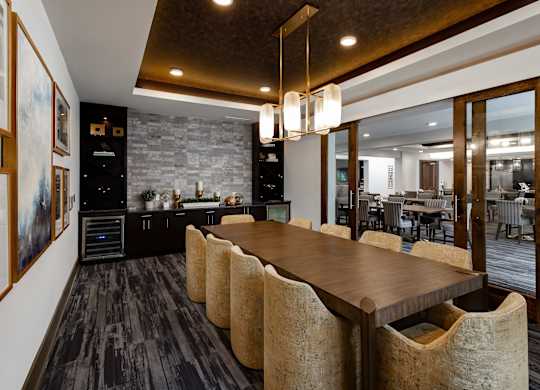 A modern kitchen with a long wooden table and chairs.