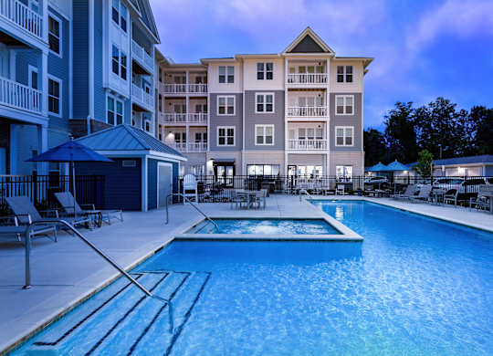 A swimming pool in front of a multi-story apartment building.