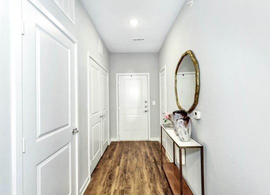 a hallway with white walls and white doors and a mirror at Farmhaus Apartments, Madison