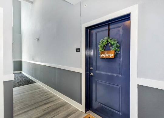 a hallway with a blue door with a wreath on it at Farmhaus Apartments, Madison, AL