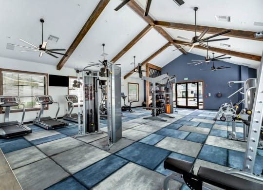 a gym with weights and cardio equipment and a ceiling with wooden beams at Farmhaus Apartments, Madison, AL, 35757