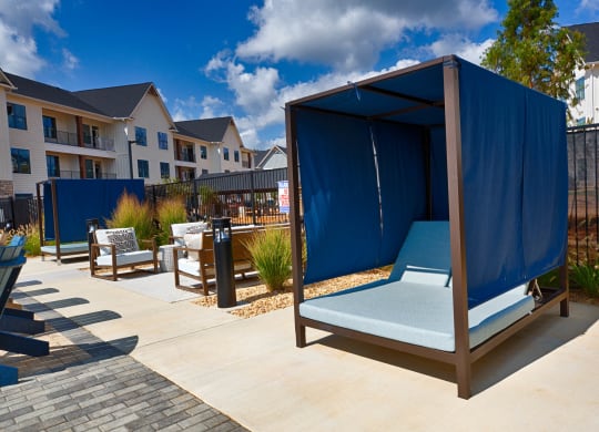 an outdoor lounge area with a blue tent in front of an apartment building at Farmhaus Apartments, Madison, Alabama