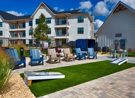 a patio with chairs and a table in front of an apartment building at Farmhaus Apartments, Madison, AL