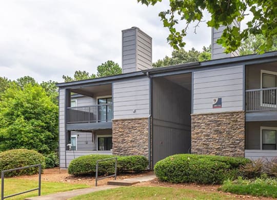 a white and gray apartment building with trees and bushes at High Ridge Apartments, Athens