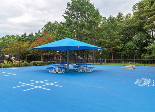 a blue tennis court with tables and a blue umbrella at High Ridge Apartments, Athens, GA 30606