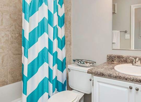 A bathroom with a white toilet, a sink, and a shower curtain. at Bradford Pointe, Georgia, 30909