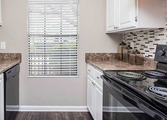 A kitchen with white cabinets and a black stove top oven. at Bradford Pointe, Augusta