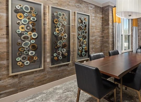a dining room with a table and chairs and paintings on the wall at The Flats at Southlawn Apartments, Georgia