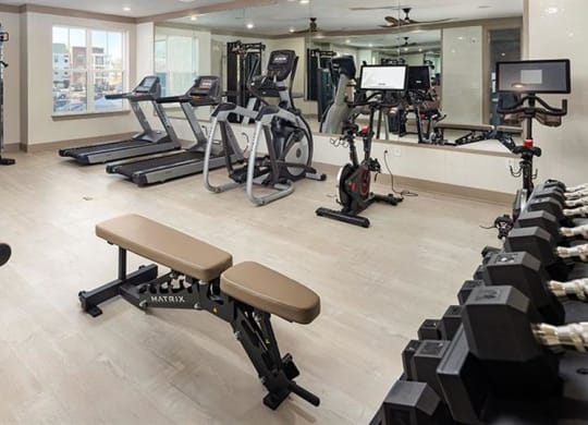 a gym with various exercise equipment on the floor and a window at The Flats at Southlawn Apartments, Lawrenceville, GA 30046