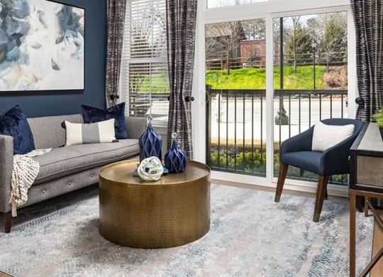 a living room with a couch and a door to a balcony at The Flats at Southlawn Apartments, Lawrenceville, GA 30046