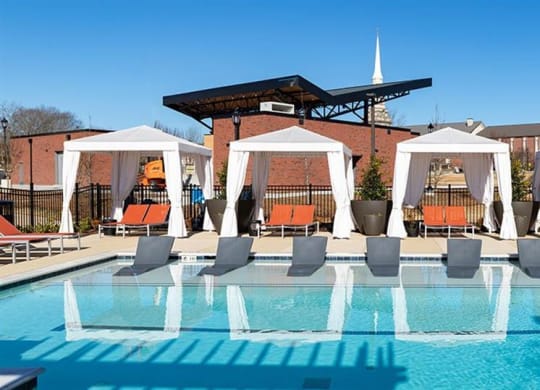 a swimming pool with chairs and umbrellas at The Flats at Southlawn Apartments, Lawrenceville, GA