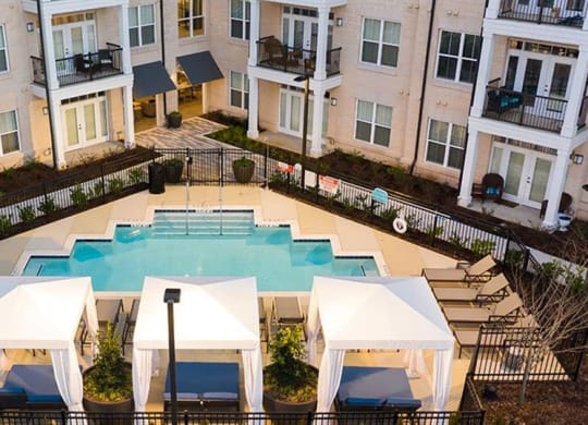 an aerial view of a swimming pool in front of an apartment building at The Flats at Southlawn Apartments, Georgia