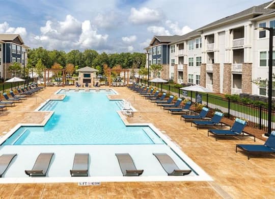 an outdoor pool with lounge chairs and umbrellas at an apartment building at Promenade at Newnan Crossing, Georgia