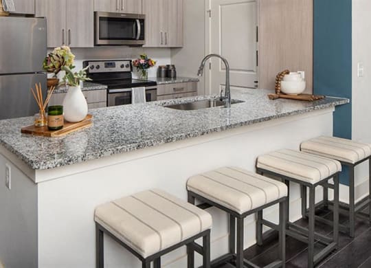 a kitchen with a counter with four stools at Promenade at Newnan Crossing, Georgia