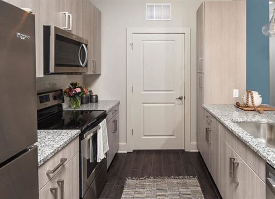 a kitchen with stainless steel appliances and marble counter tops at Promenade at Newnan Crossing, Newnan