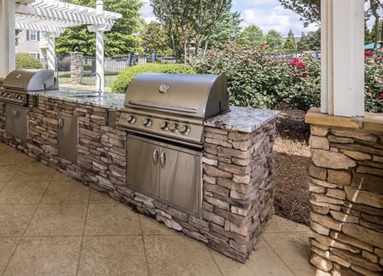an outdoor kitchen with two grills on a patio at Bedford Parke Apartments, Georgia, 31088