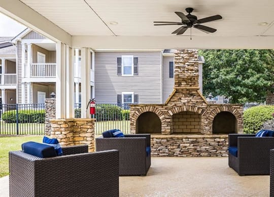 a covered patio with a stone fireplace and chairs at Bedford Parke Apartments, Warner Robins, GA 31088