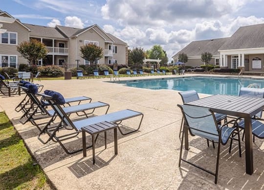a swimming pool with tables and chairs around it at Bedford Parke Apartments, Warner Robins