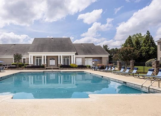 a pool with chairs around it in front of a house at Bedford Parke Apartments, Georgia