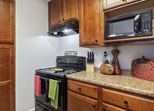 a kitchen with a stove and a microwave at Bedford Parke Apartments, Warner Robins