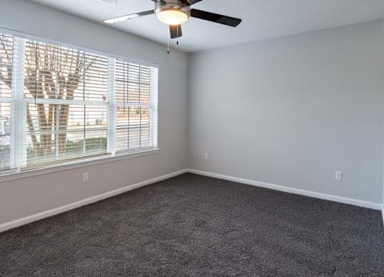 A room with a ceiling fan and a window with blinds.
