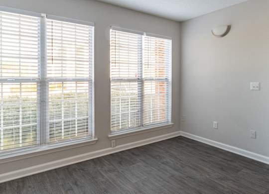 A room with two windows covered in white blinds.