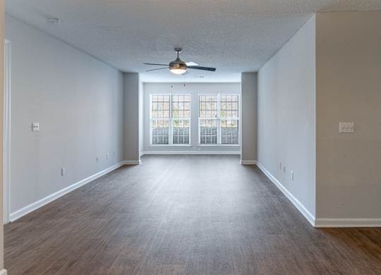 A spacious room with a ceiling fan and a sliding glass door.
