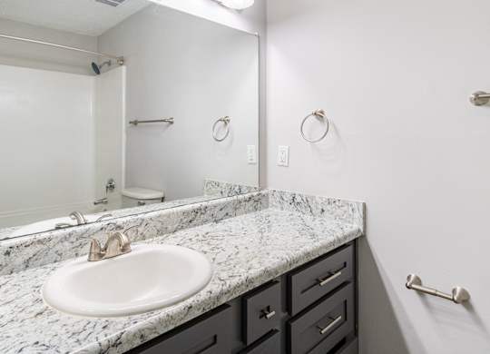 A bathroom with a marble countertop and a white sink.