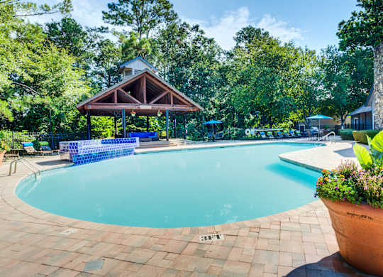 A pool surrounded by trees and a pavilion.