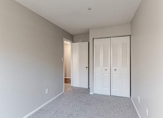 A room with a white door and a grey carpet.